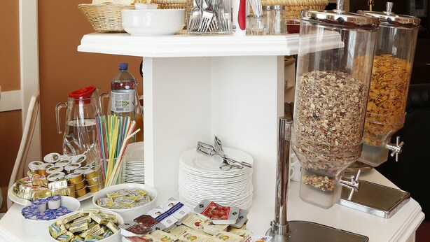 A buffet table with various food items, utensils, and condiments.