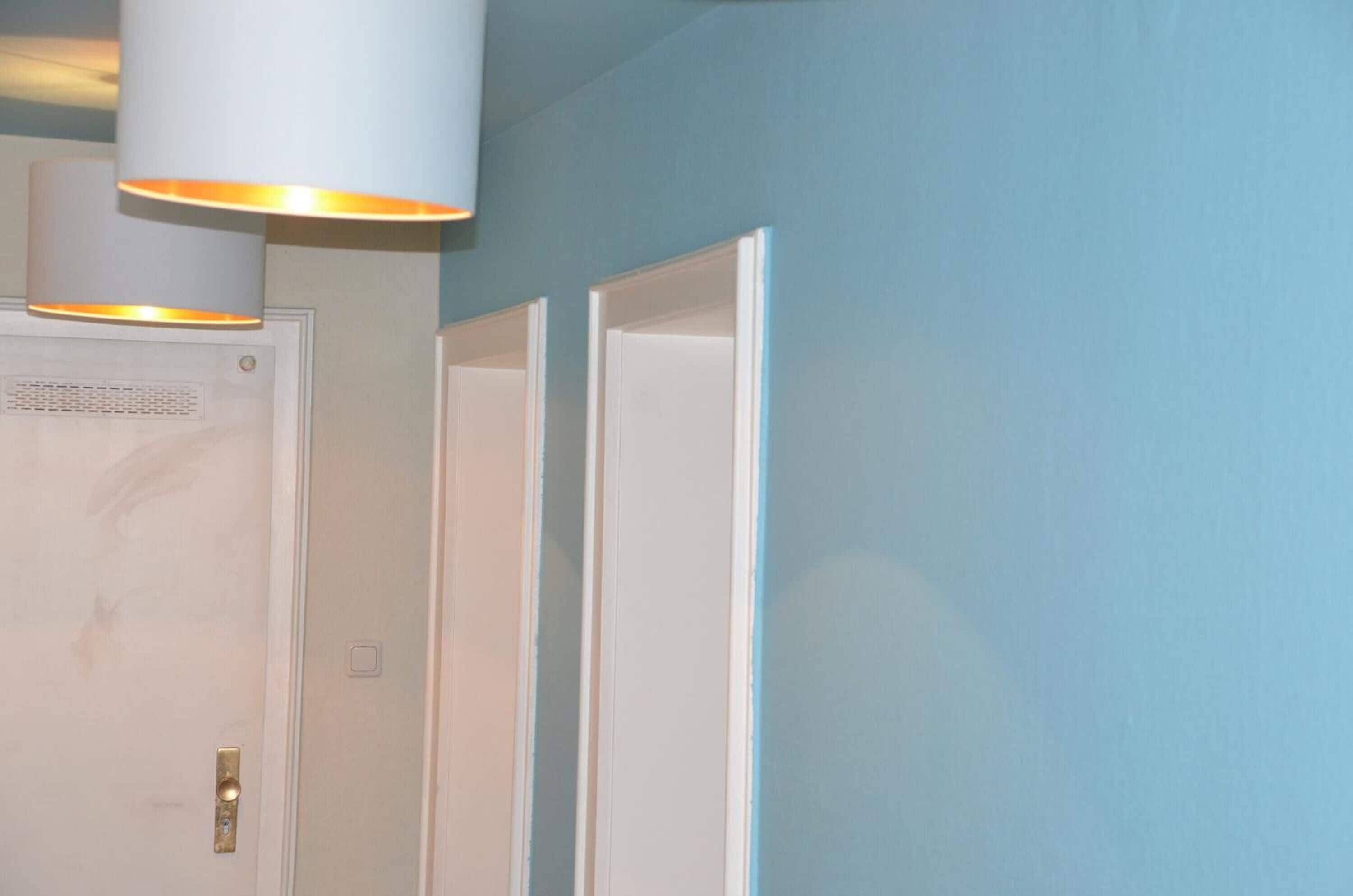 A room with a white door, a light fixture above it, and a blue wall.