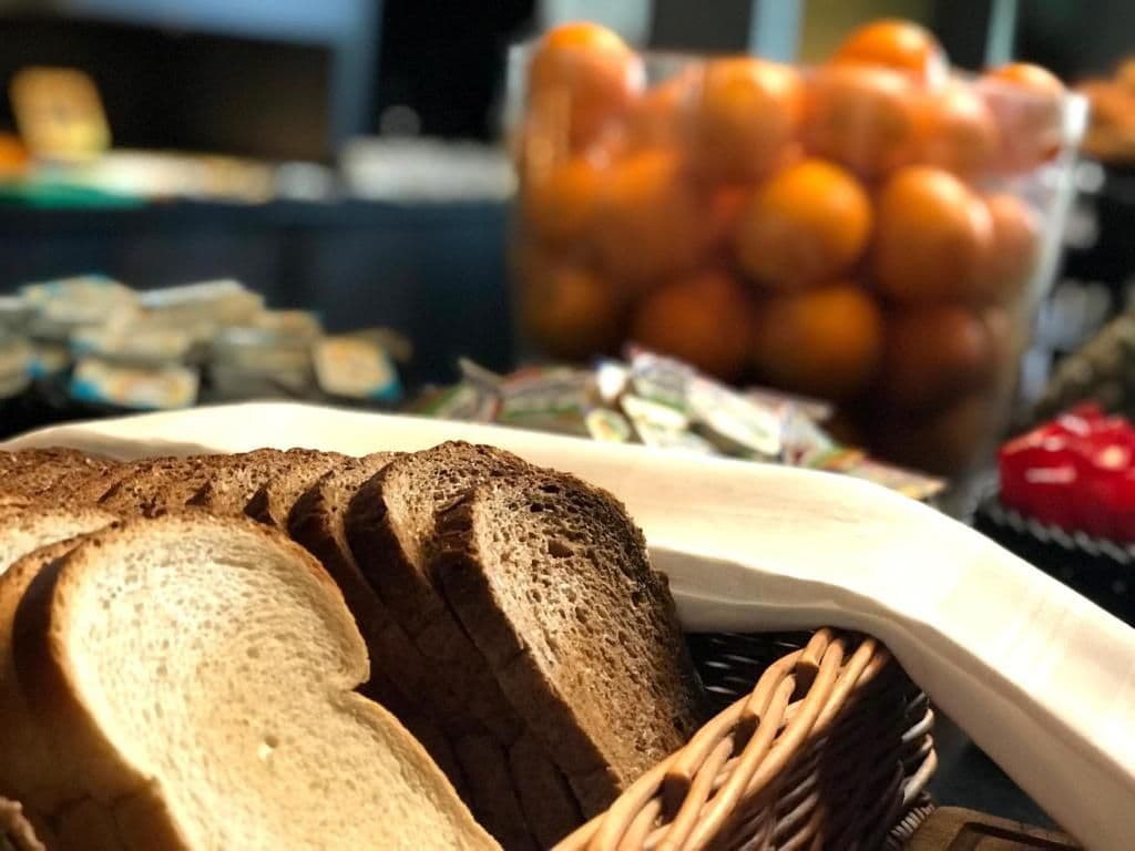A basket of sliced bread and a container of oranges on a table.