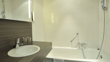 Un baño moderno con un lavamanos blanco, un espejo, ducha con cabezal de ducha manual y una toalla colgada en la pared.