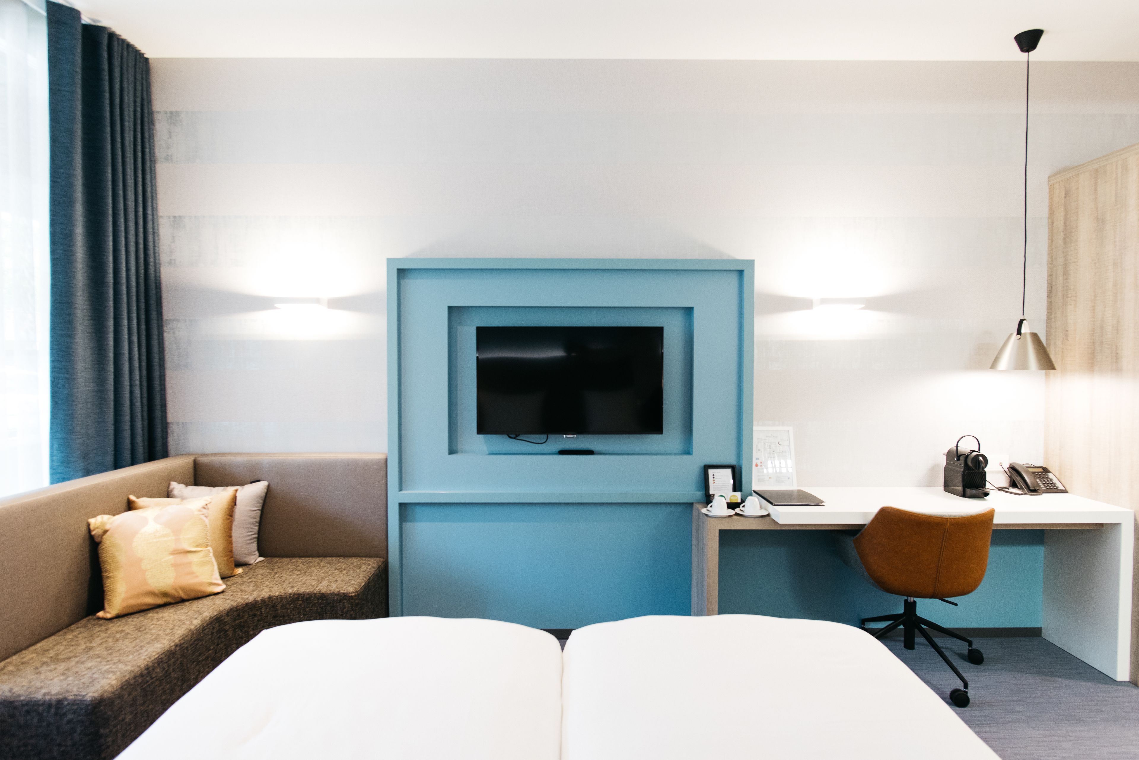 Ett hotellrum med en säng, ett skrivbord, en tv och en soffa.