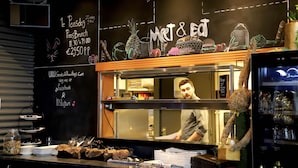 Un restaurant avec un menu écrit à la craie, une pancarte « Bienvenue » et une autre pancarte « Met & Ed » au-dessus du comptoir.