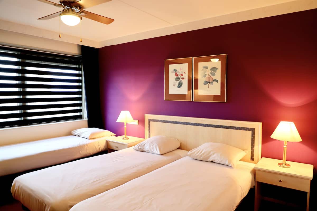 Ein Hotelzimmer mit zwei Betten, einem Deckenventilator und Bildern an der Wand.