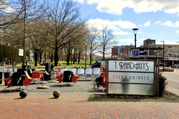 A sign for 'Traagduys' with outdoor seating and a parking sign nearby.