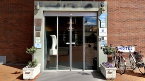 L’entrée de l’hôtel, avec sa façade en briques, ses portes en verre et une enseigne au-dessus.