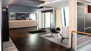 A modern interior with a bar area, seating, and a staircase. - B&B HOTEL Dresden City-Süd (Dresden)