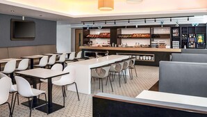 A modern restaurant with a bar area, seating, and a television screen. - B&B HOTEL Dresden City-Süd (Dresden)