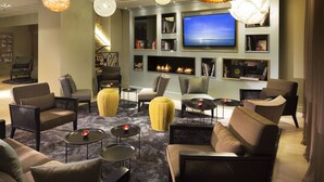 A modern lounge area with comfortable seating, a flat-screen TV, and a fireplace. - Hôtel Oceania Le Jura Dijon (Dijon)