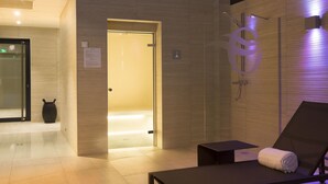 Un moderno cuarto de spa con una camilla de masaje, una toalla y una zona de ducha.