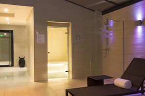 A modern spa room with a massage table, a towel, and a shower area. - Hôtel Oceania Le Jura Dijon (Dijon)