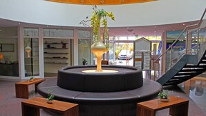 A modern lobby with a central seating area, glass walls, and a staircase. - City Hotel Frankfurt am Main Bad Vilbel (Bad Vilbel)