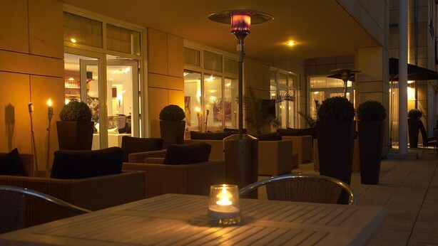 An outdoor seating area with tables, chairs, and potted plants. - City Hotel Frankfurt am Main Bad Vilbel (Bad Vilbel)