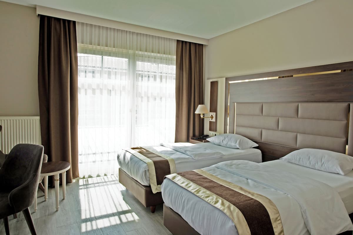 Une chambre d’hôtel avec deux lits, un bureau et une chaise.