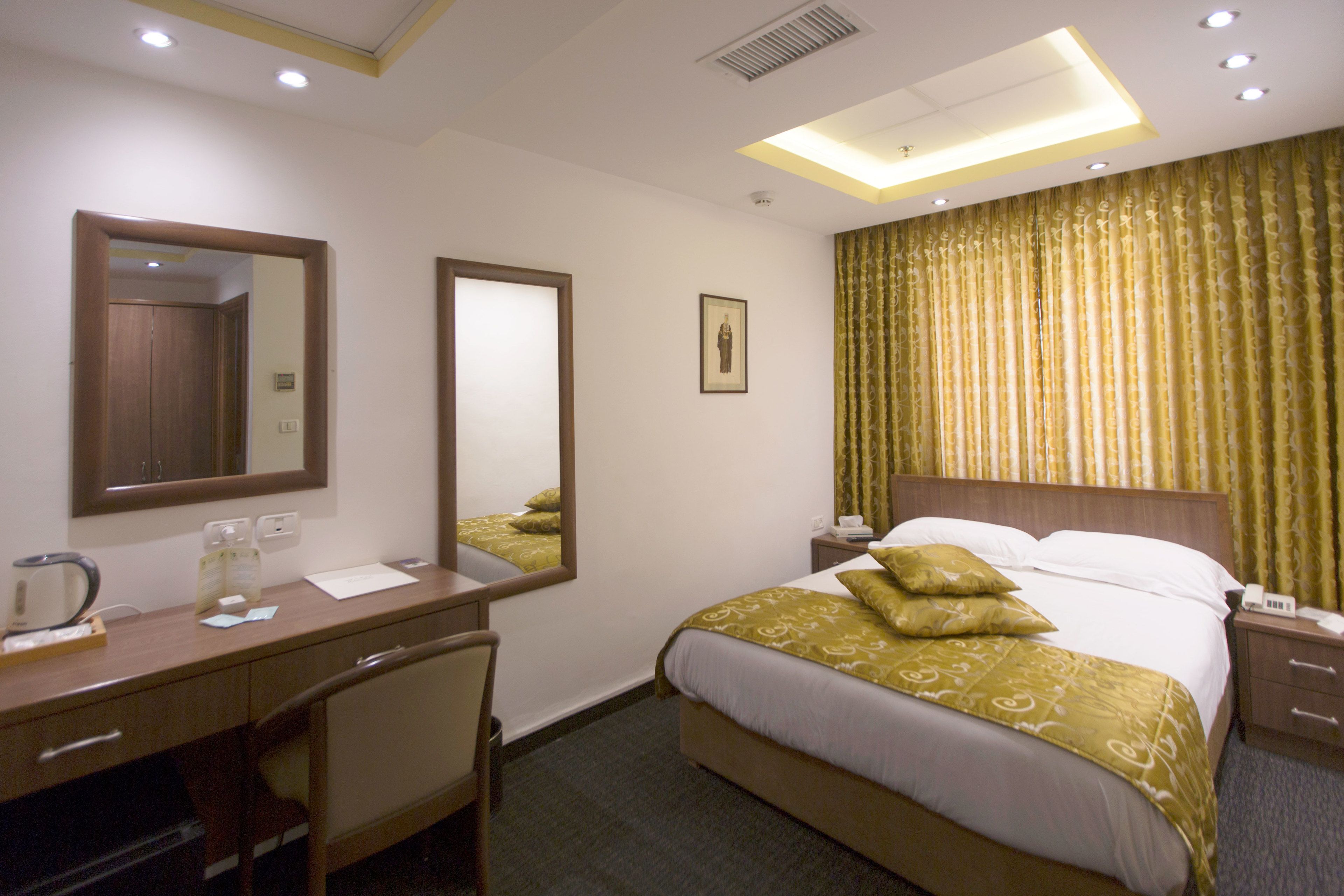 Ein Hotelzimmer mit Bett, Schreibtisch, Stuhl, Spiegel und Nachttisch.