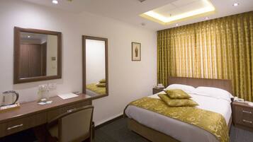 Ein Hotelzimmer mit Bett, Schreibtisch, Stuhl, Spiegel und Nachttisch.