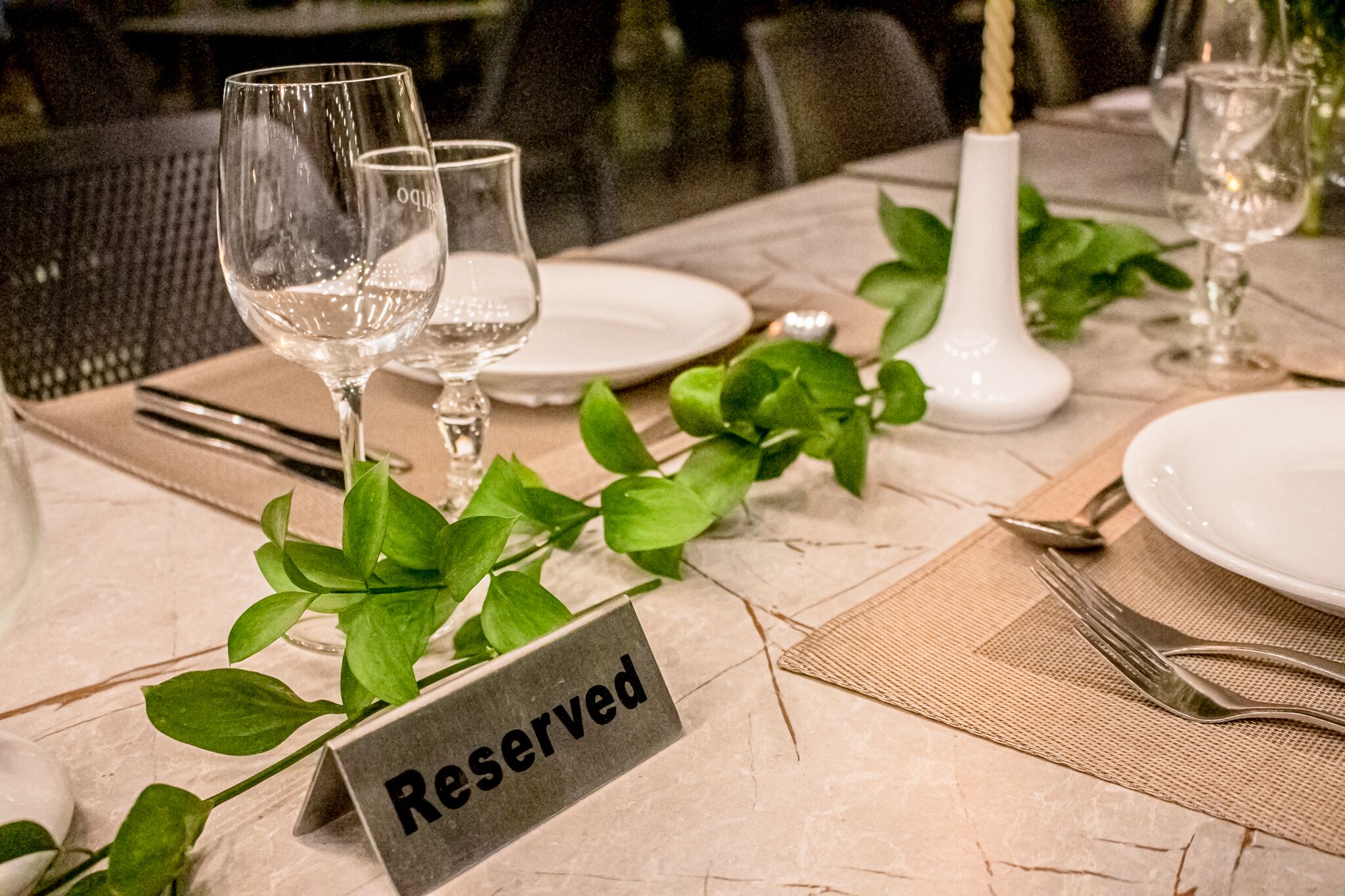 Una mesa dispuesta con copas de vino, platos y un cartel que dice 'Reservado', indicando un área de comedor.