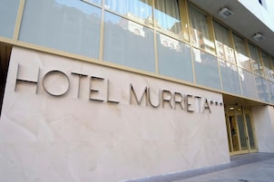 Entrada de hotel com uma grande placa indicando 'HOTEL MURRETA'.