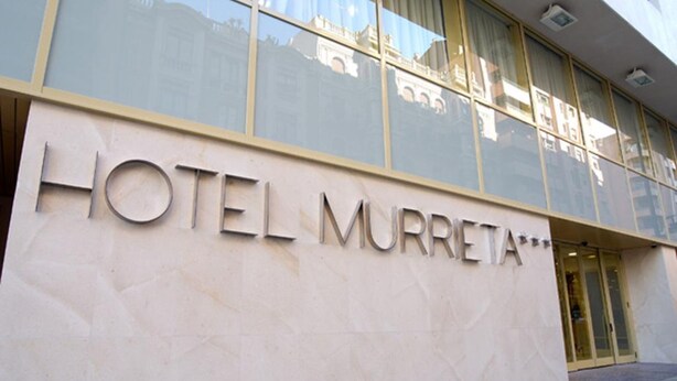 L’extérieur de l’HÔTEL MURRETA se distingue par sa façade moderne, ses grandes fenêtres et son entrée imposante.
