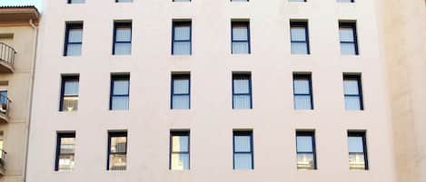 A multi-story hotel with a flat facade, numerous windows, and a ground-level entrance with a sign.
