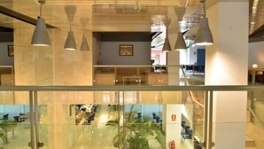 Un intérieur moderne avec des cloisons en verre, des luminaires suspendus et un espace salon central.