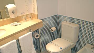 A bathroom with a toilet, bidet, sink, and a mirror.