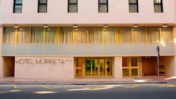 Fachada de hotel con una entrada amplia, numerosas ventanas y un cartel que dice 'HOTEL MURRITA'.