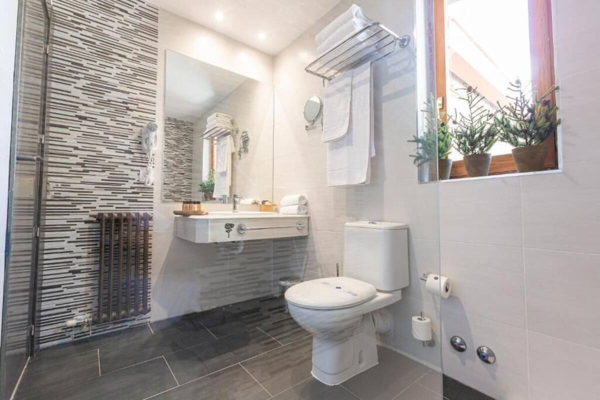 Une salle de bain moderne avec une douche à parois de verre, des toilettes, un lavabo avec un miroir et un porte-serviettes.