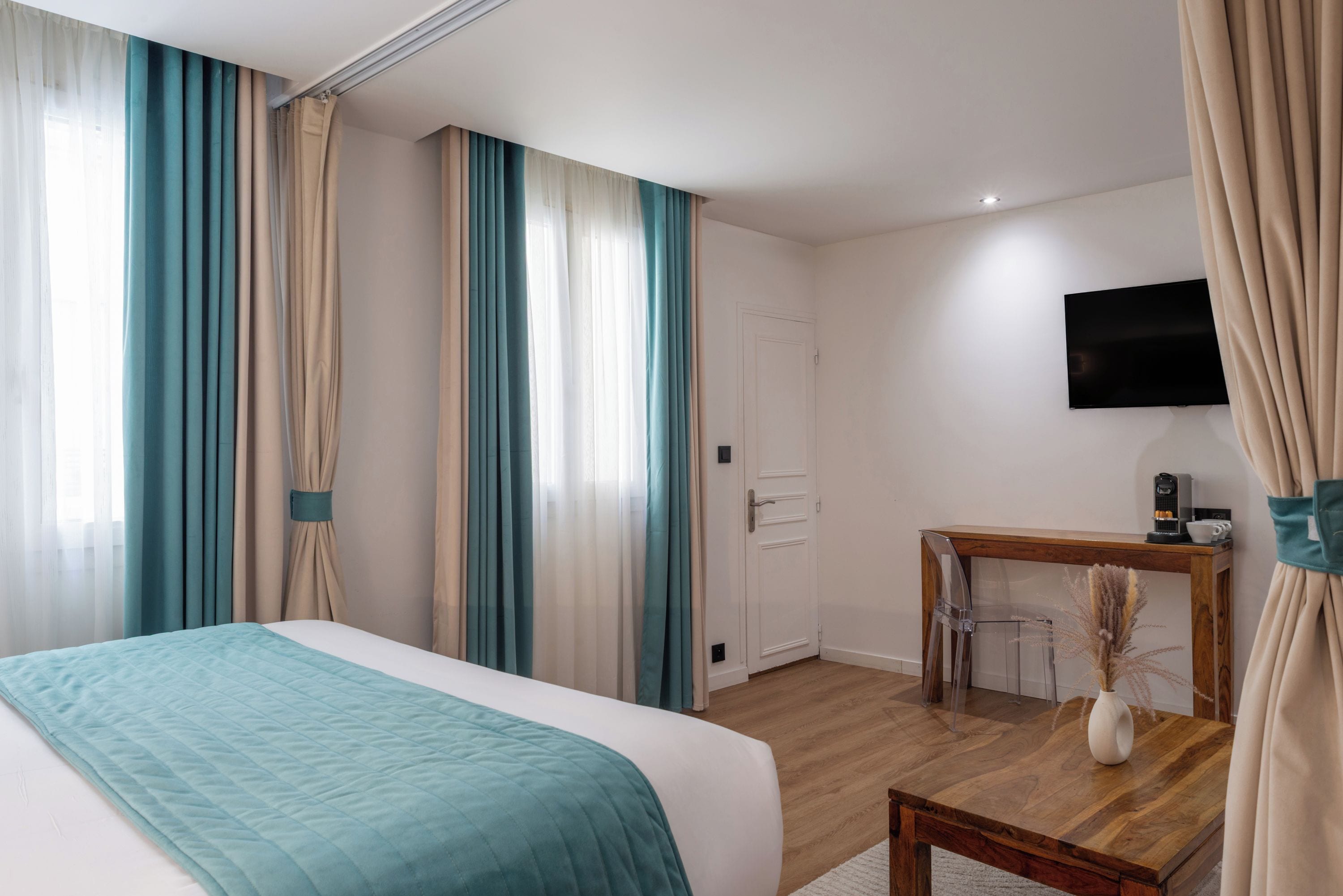 A hotel room with a bed, a desk, a TV, and curtains.