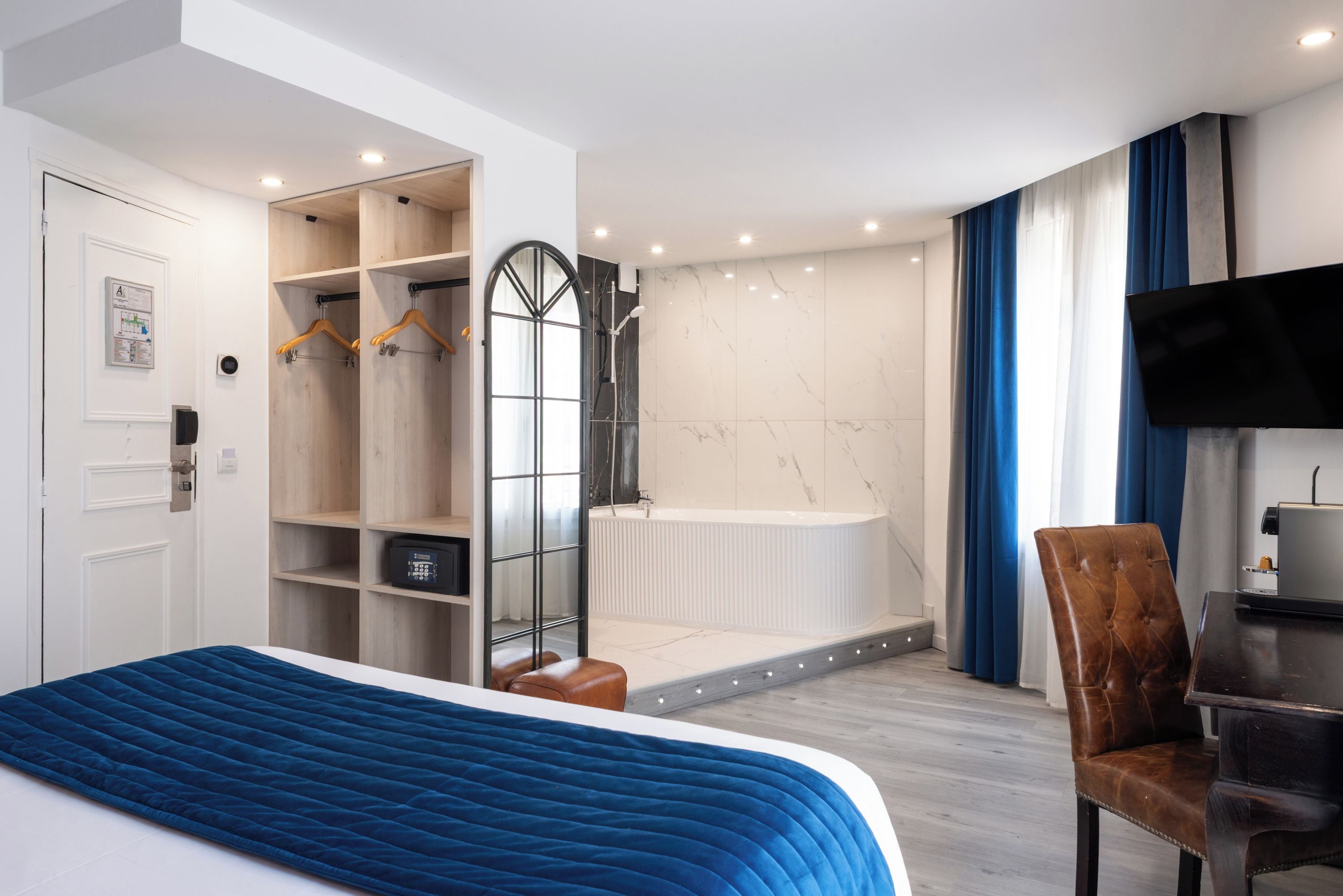 Une chambre d’hôtel moderne dotée d’un grand lit, d’un coin salon, d’une douche et d’une télévision.