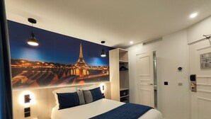 A hotel room with a large bed, a wardrobe, a mirror, and a wall-mounted picture of the Eiffel Tower. - Atelier Montparnasse (Paris)