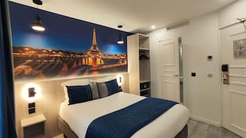 Habitación de hotel con una cama grande, un armario, un espejo y un cuadro colgado en la pared de la Torre Eiffel.