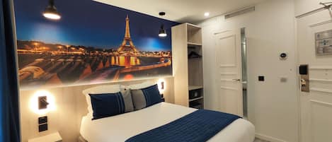 Habitación de hotel con una cama grande, un armario, un espejo y un cuadro colgado en la pared de la Torre Eiffel.