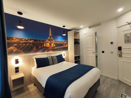 Habitación de hotel con una cama grande, un armario, un espejo y un cuadro colgado en la pared de la Torre Eiffel.