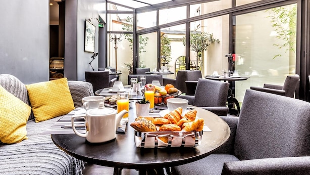 A breakfast setting with a table set for two, featuring croissants, orange juice, and coffee. - Atelier Montparnasse (Paris)
