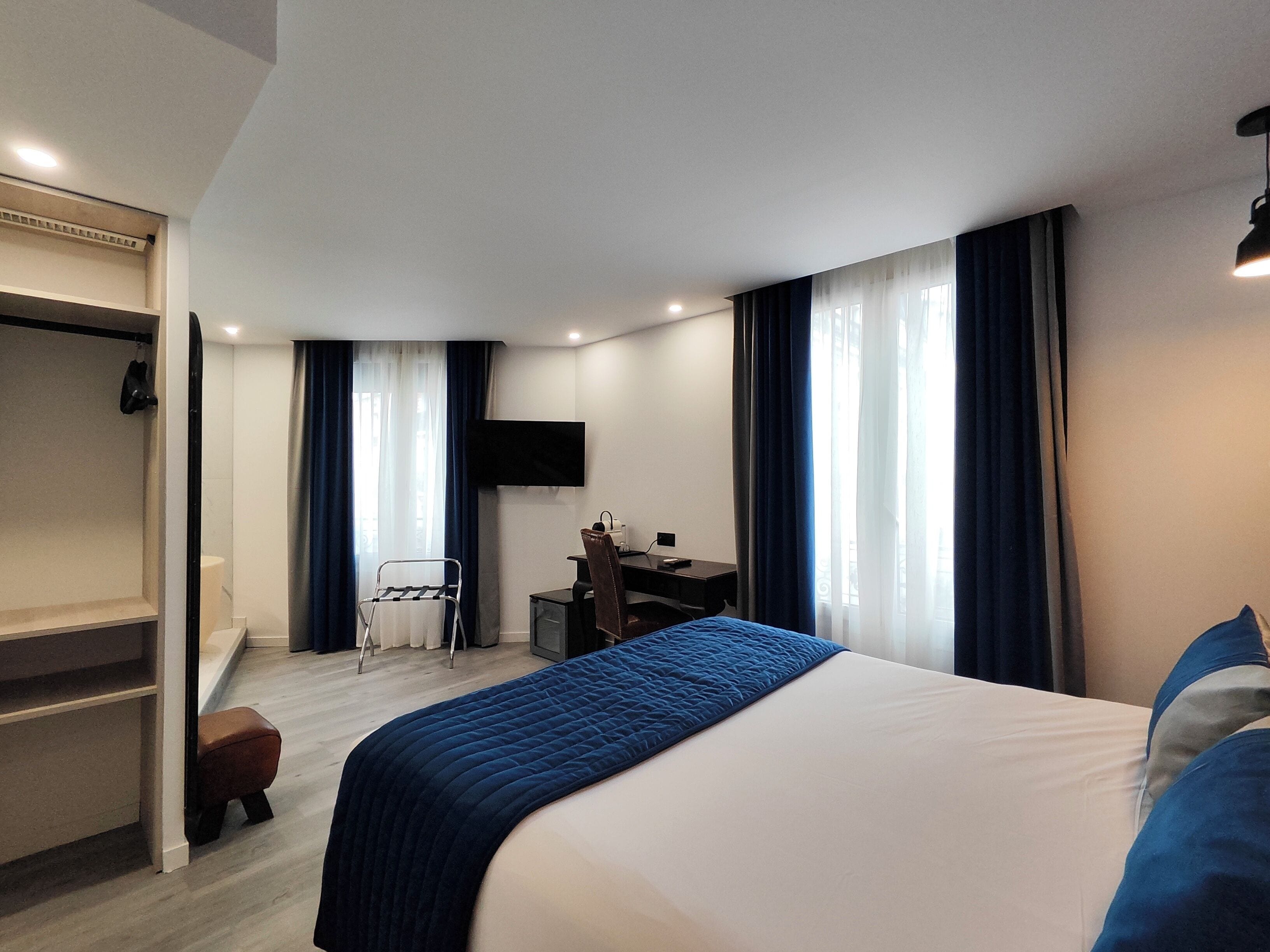 Een moderne hotelkamer met een groot bed, een bureau, een stoel, een televisie en een kledingkast.