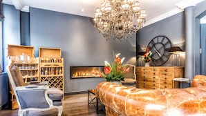 A modern living room with a leather sofa, a wooden cabinet with bottles, a fireplace, and a chandelier. - Atelier Montparnasse (Paris)