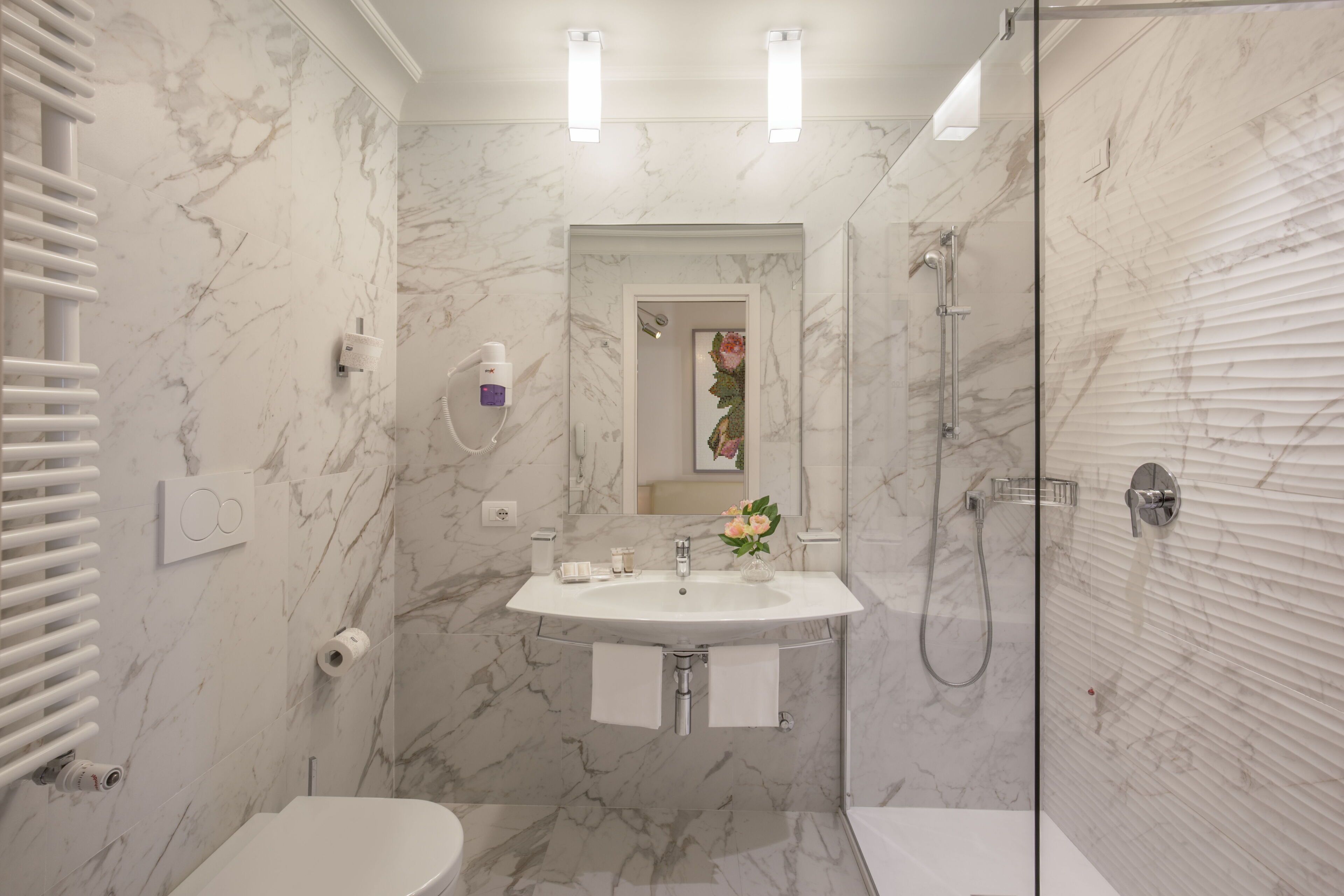Une salle de bain avec un lavabo, des toilettes et une douche, le tout en marbre.