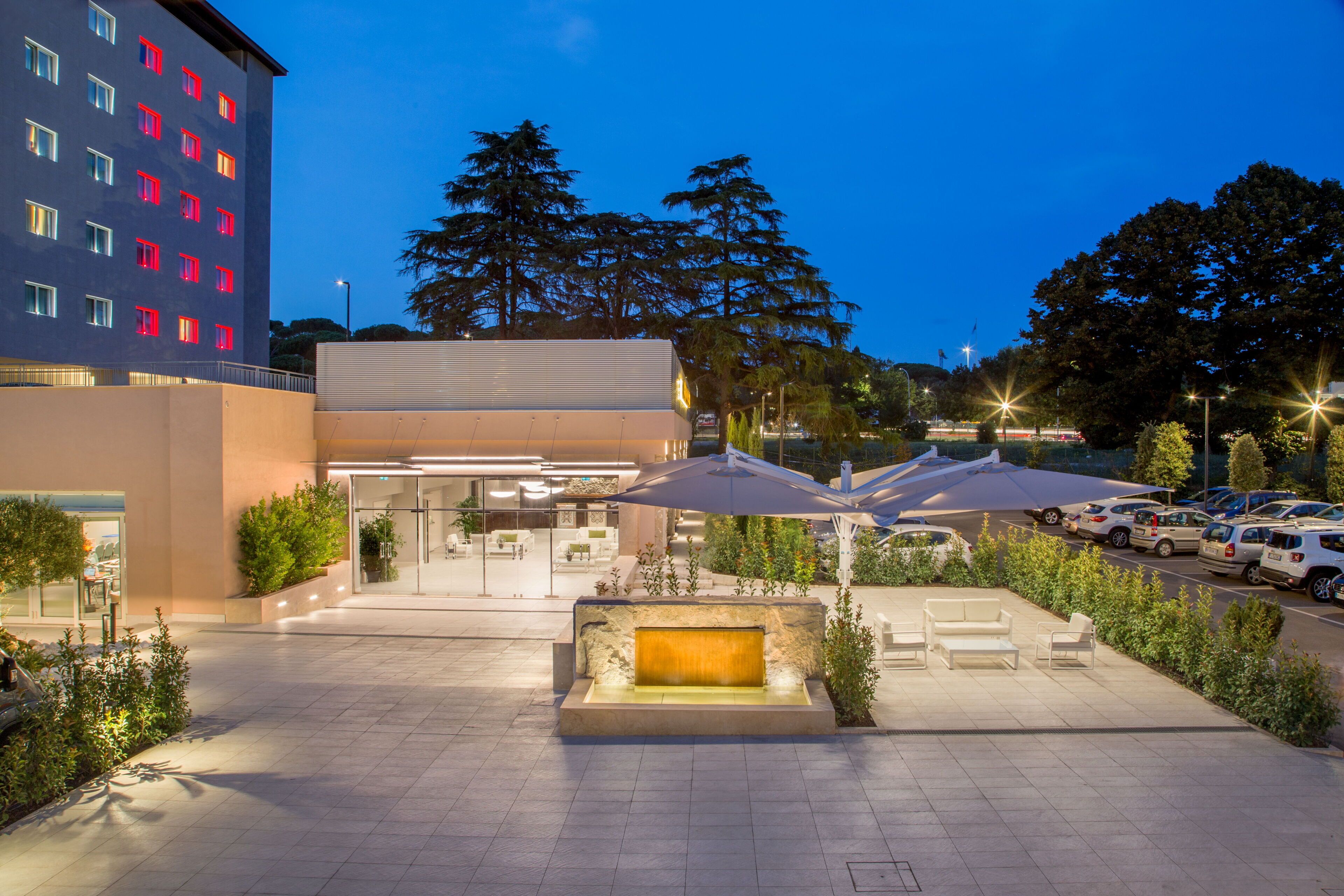 Une cour d’hôtel avec des espaces de repos en plein air, une fontaine et un parking.