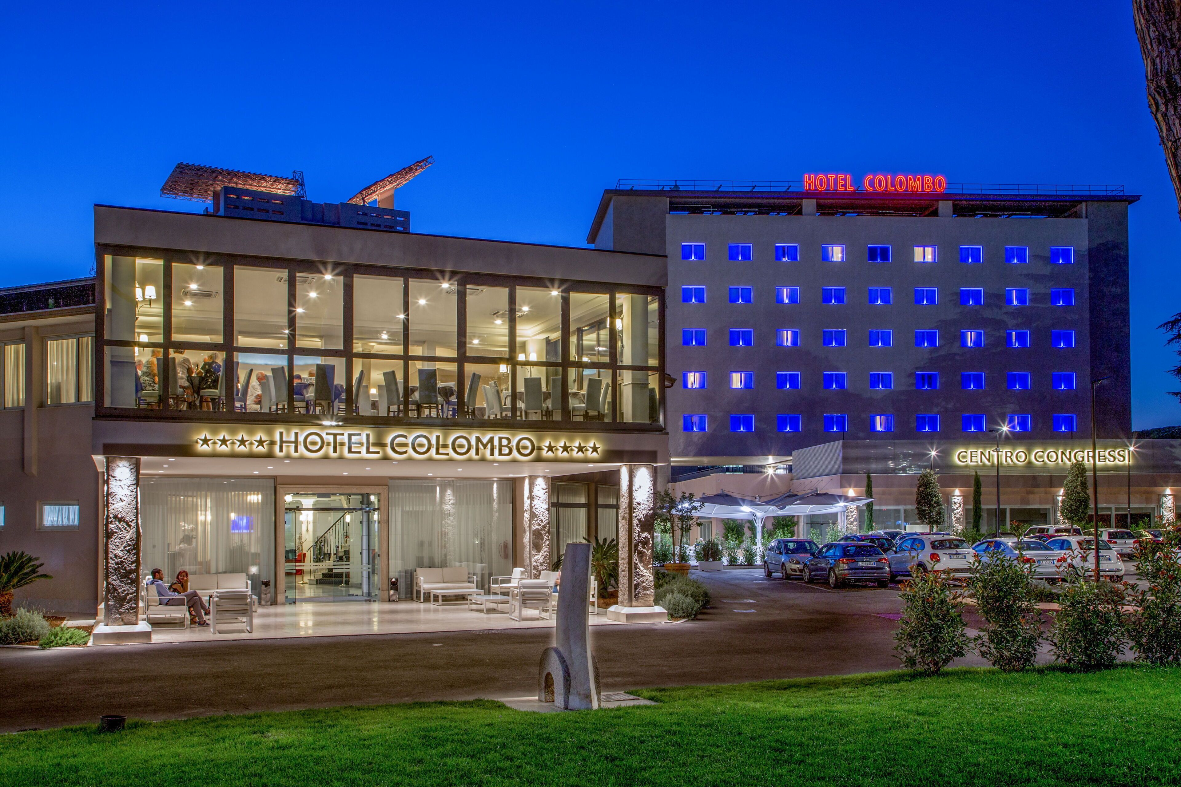 A hotel with a modern facade, large windows, and a visible outdoor seating area.