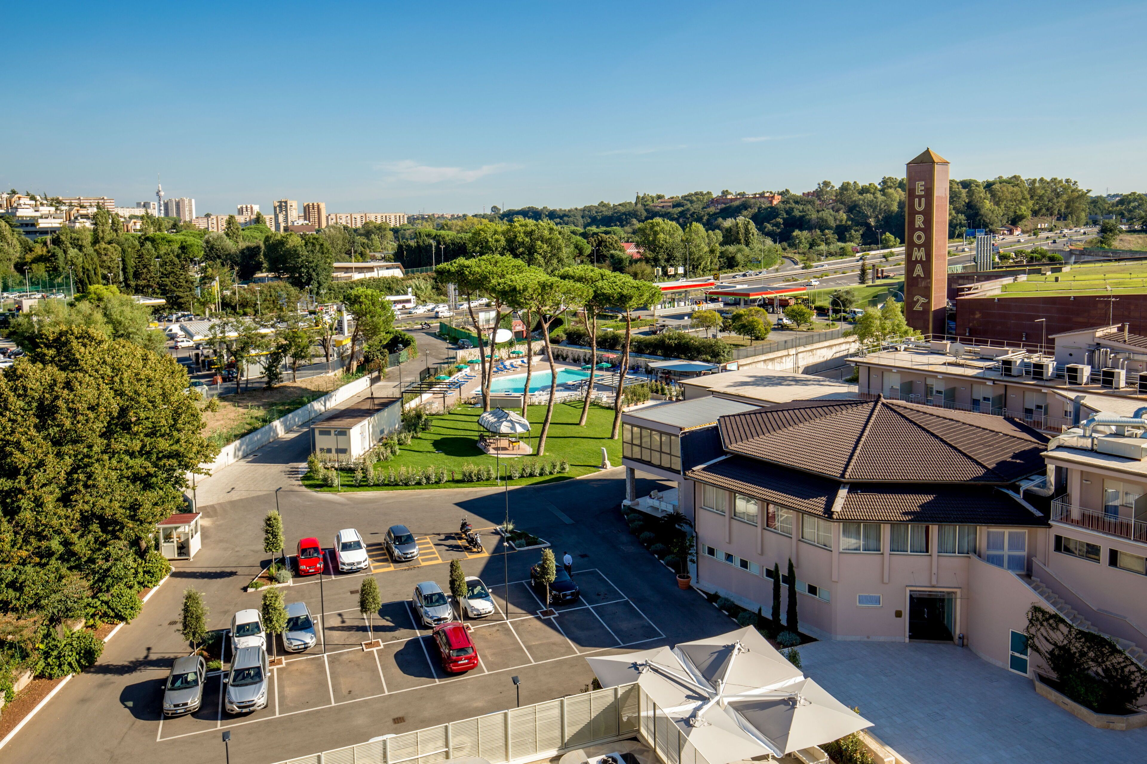 A hotel with a central courtyard, parking area, and a prominent tower.