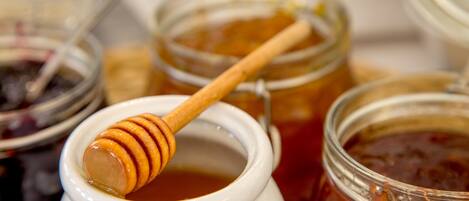 A close-up of a honey jar with a wooden dipper.