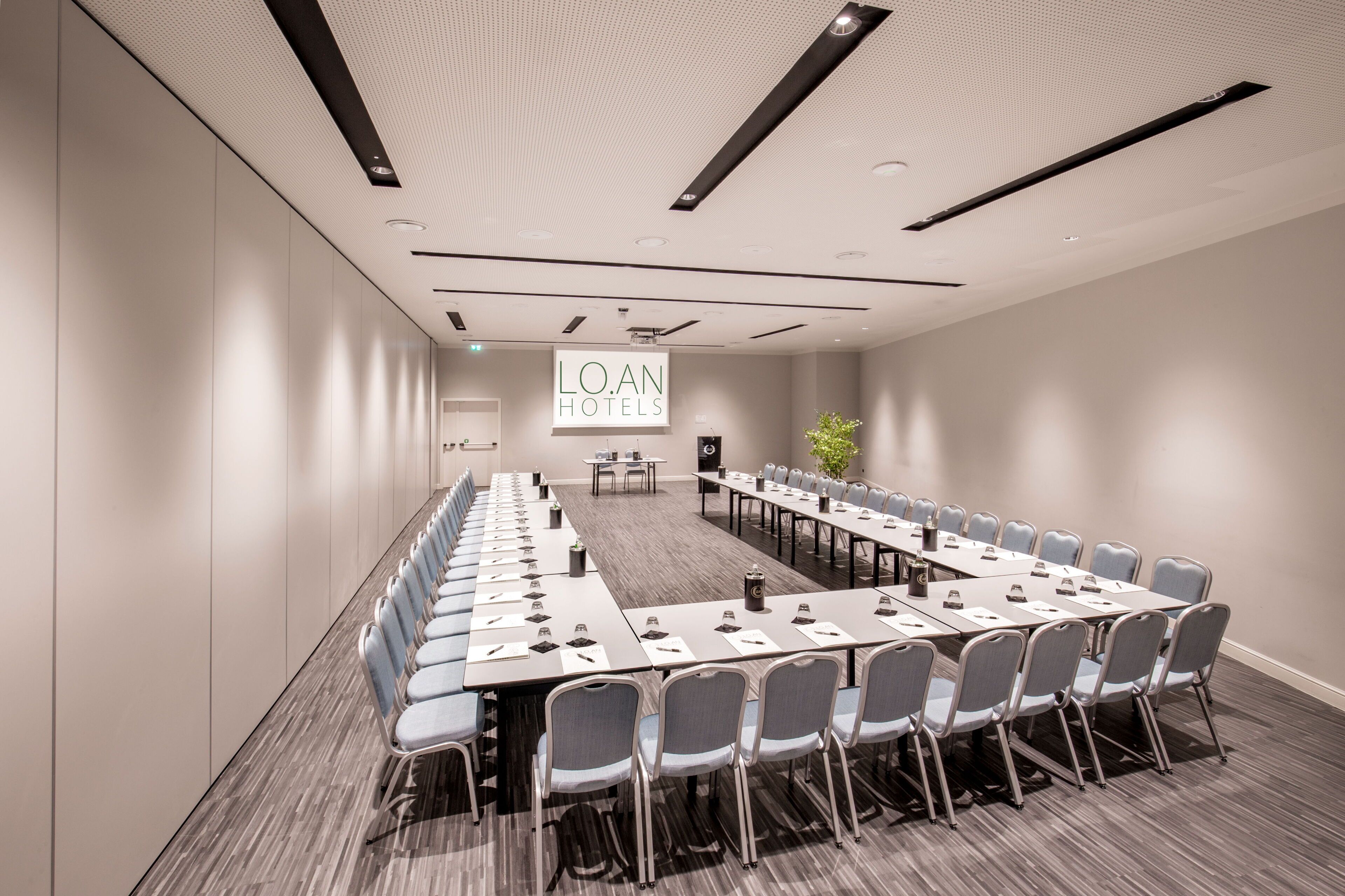 A conference room with a long table, chairs, and a sign reading "LOAN HOTELS".