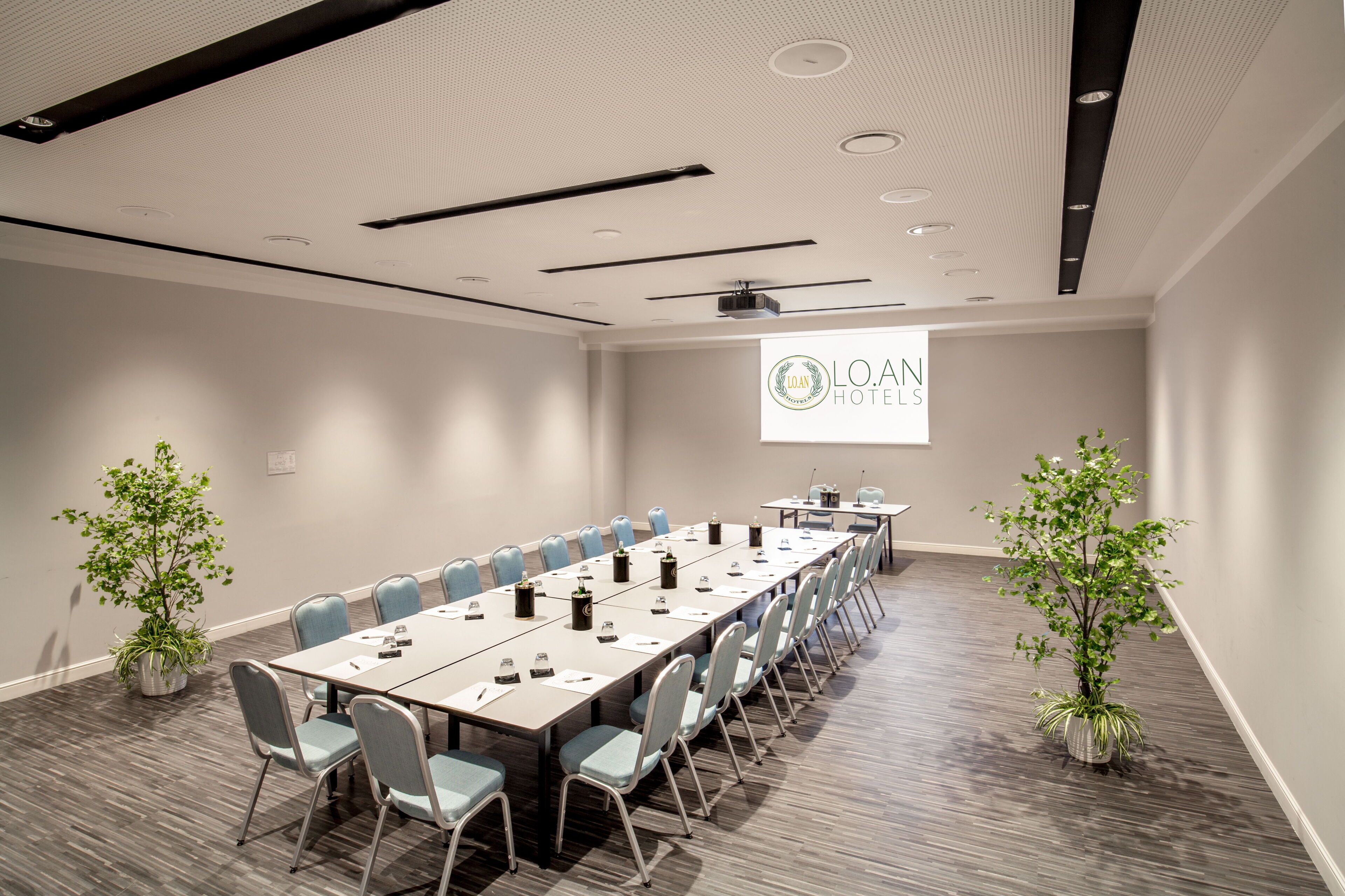 A conference room with a long table, chairs, and potted plants.