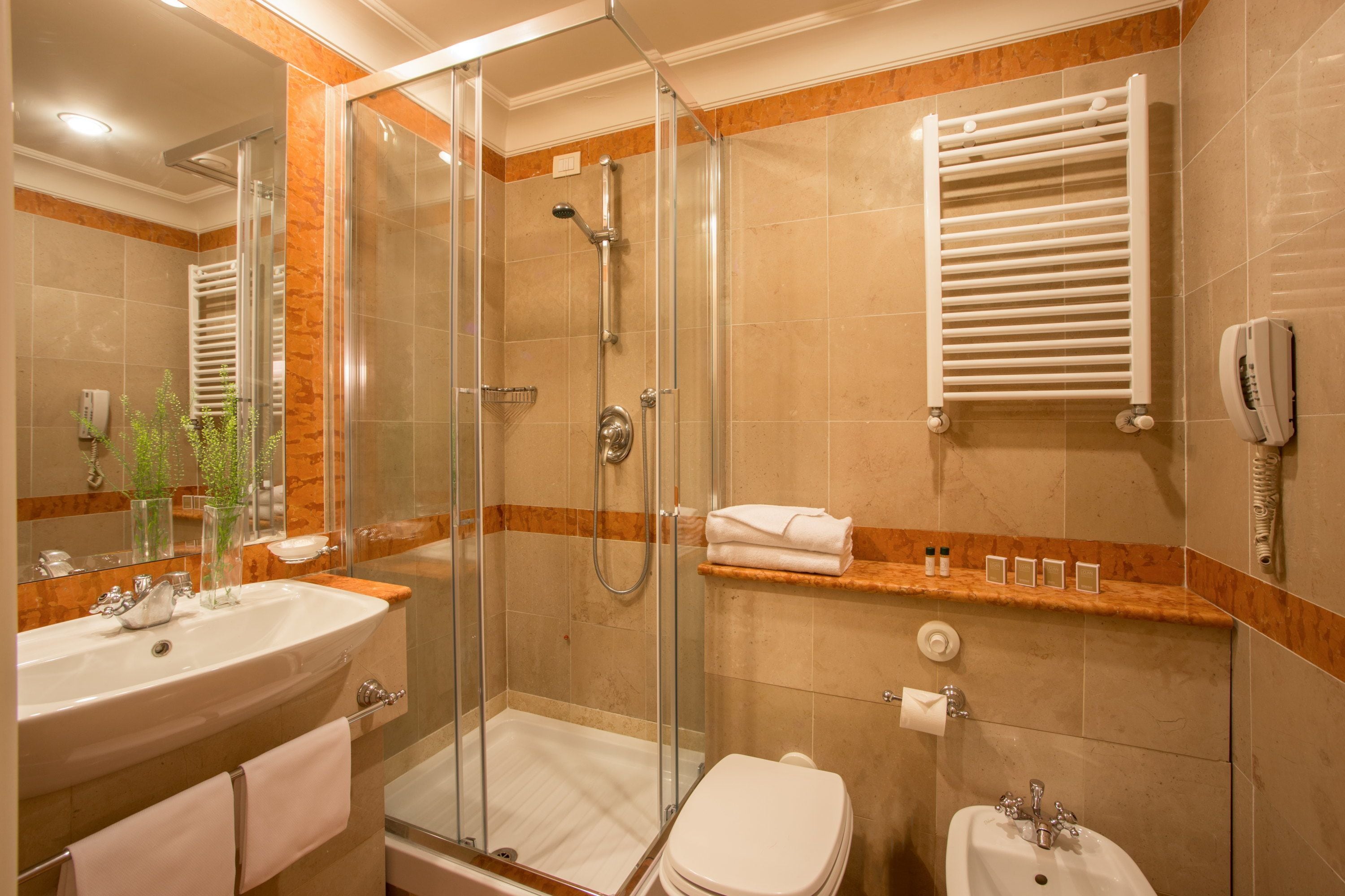 A modern bathroom with a glass-enclosed shower, a sink, and a toilet.