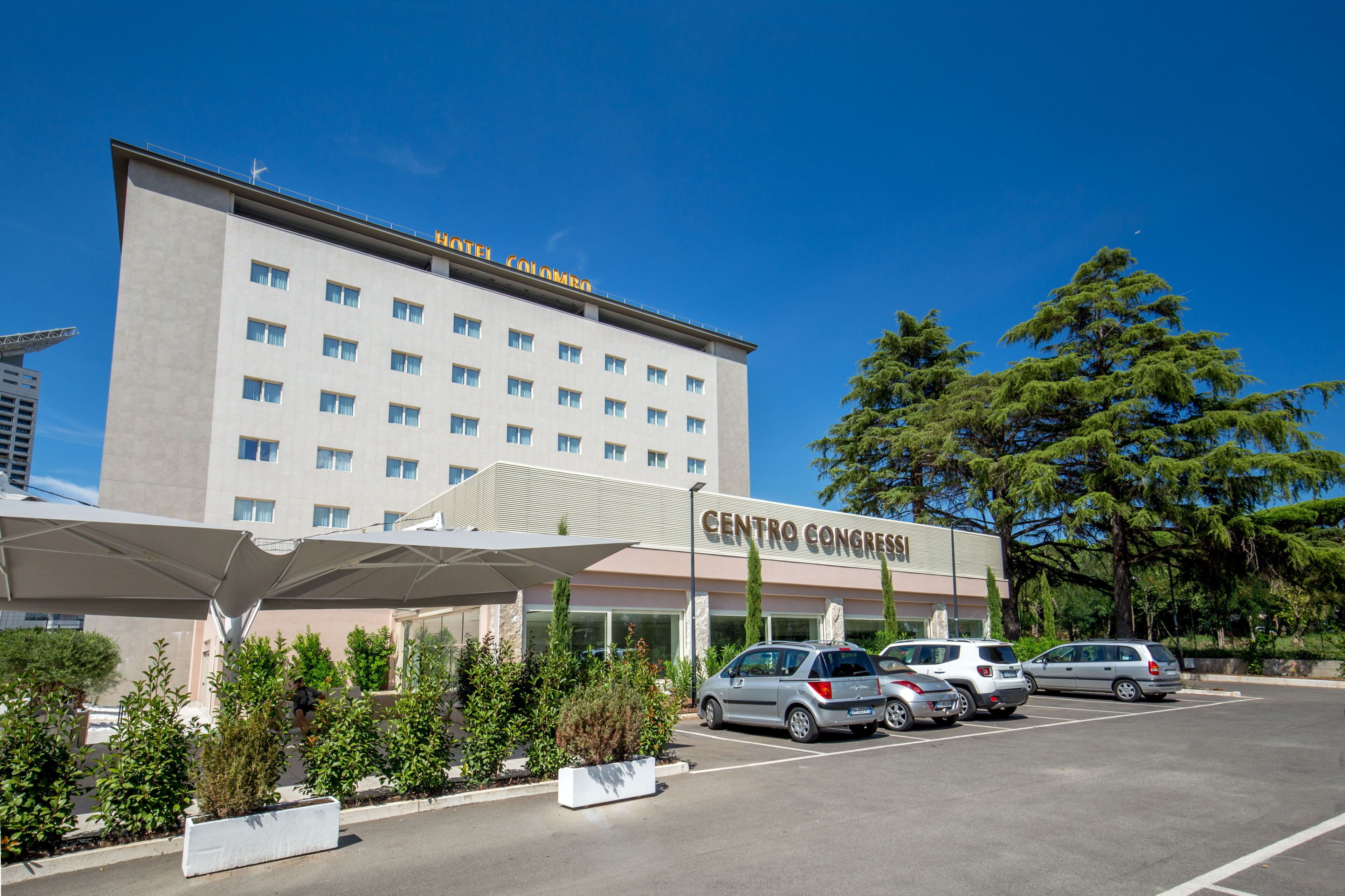 A hotel with a modern design, featuring a large parking area and a covered entrance.