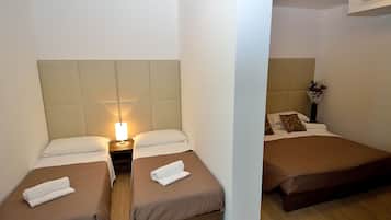 Camera d'albergo con due letti singoli, un comodino con lampada e condizionatore d'aria a parete.