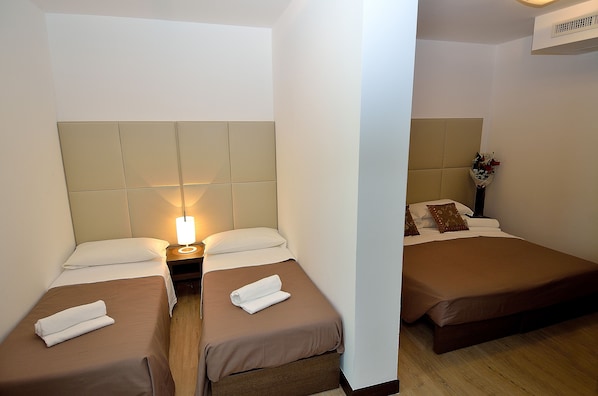 A hotel room with two single beds, a nightstand with a lamp, and a wall-mounted air conditioner. - Venice Hotel San Giuliano (Mestre)