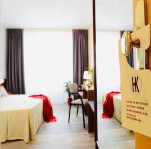 A hotel room with a bed, a desk, a chair, and a window with curtains. - Hotel Krystal (Bussolengo)