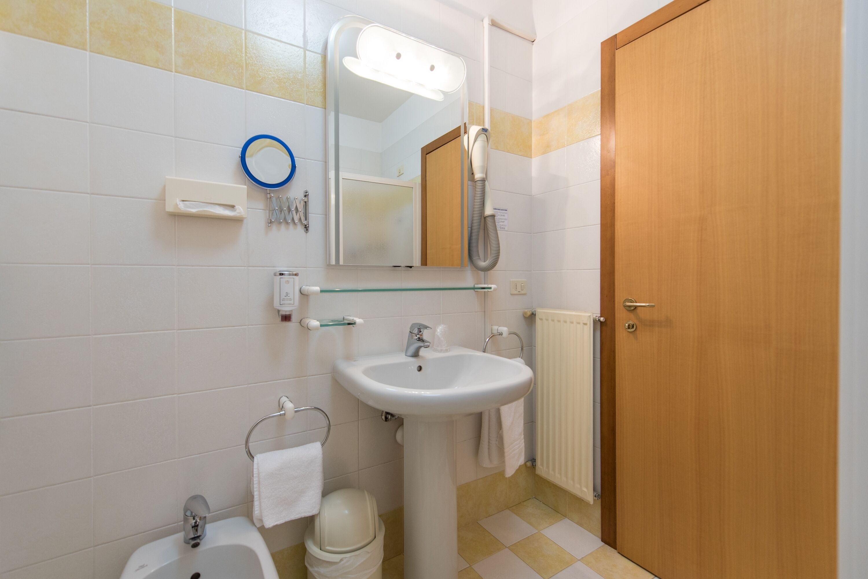 Une salle de bain équipée d’un lavabo, d’un miroir, d’un porte-serviettes et d’une douche.