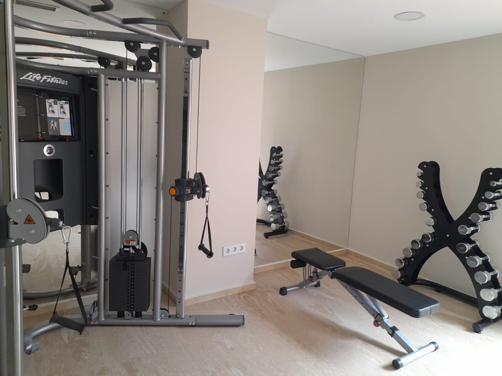 A gym with a weight bench, a squat rack, and a cable machine.